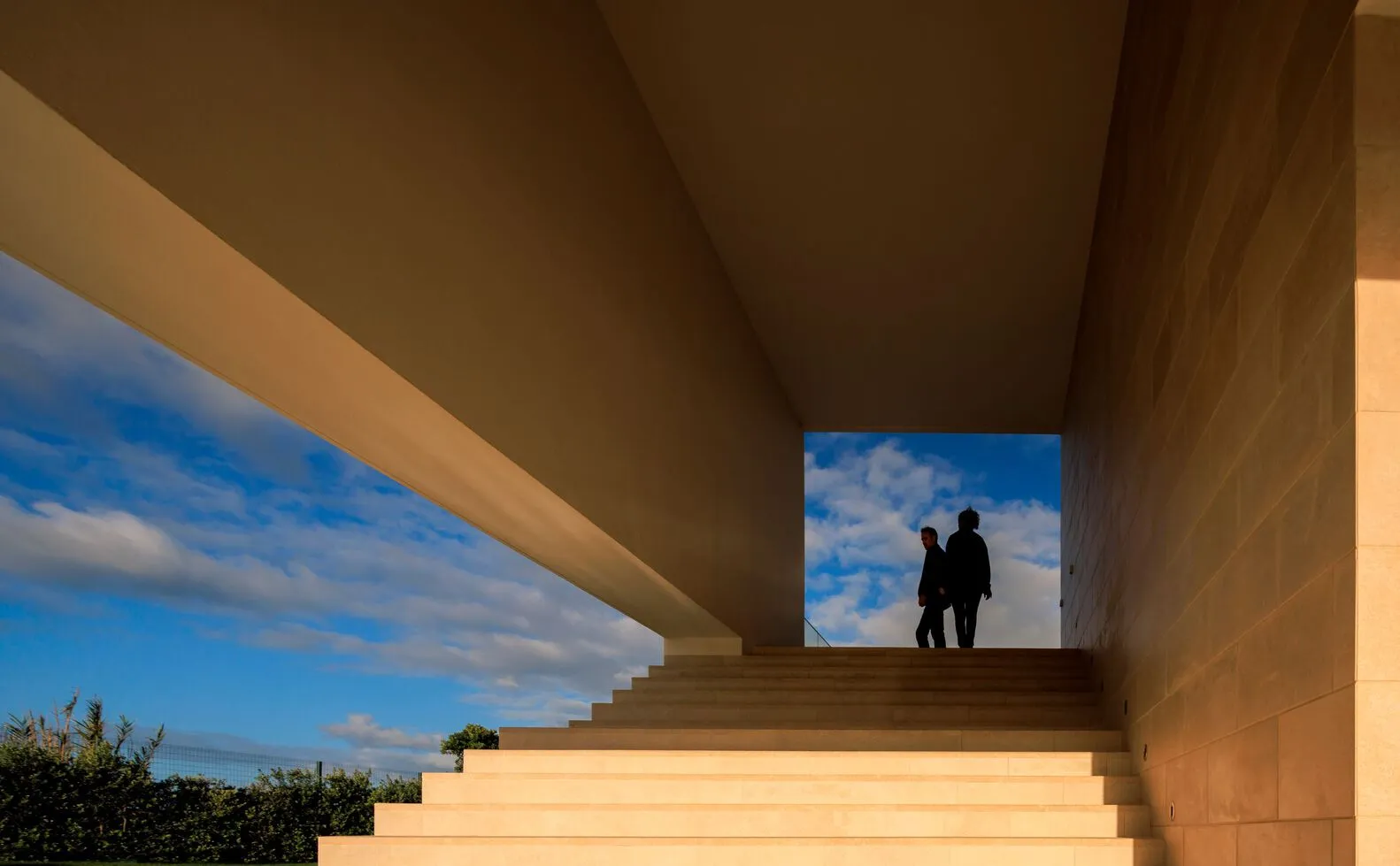 Two people walking up a set of minimalist natural stone stairs in an architecturally designed space.