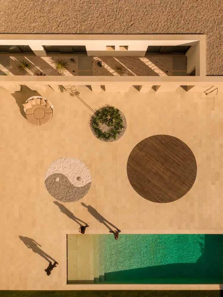 Minimalist design featuring a concrete patio with a yin-yang symbol, a wooden deck, and a swimming pool.