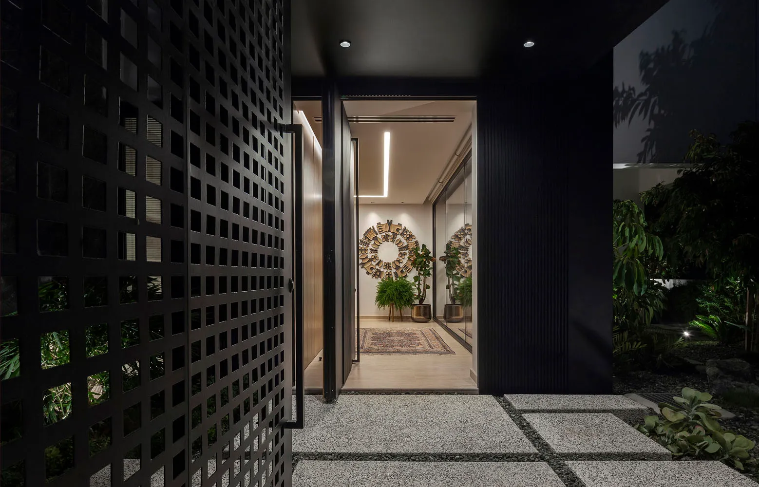 Modern entrance with glass and metal gate, concrete paving and potted plants