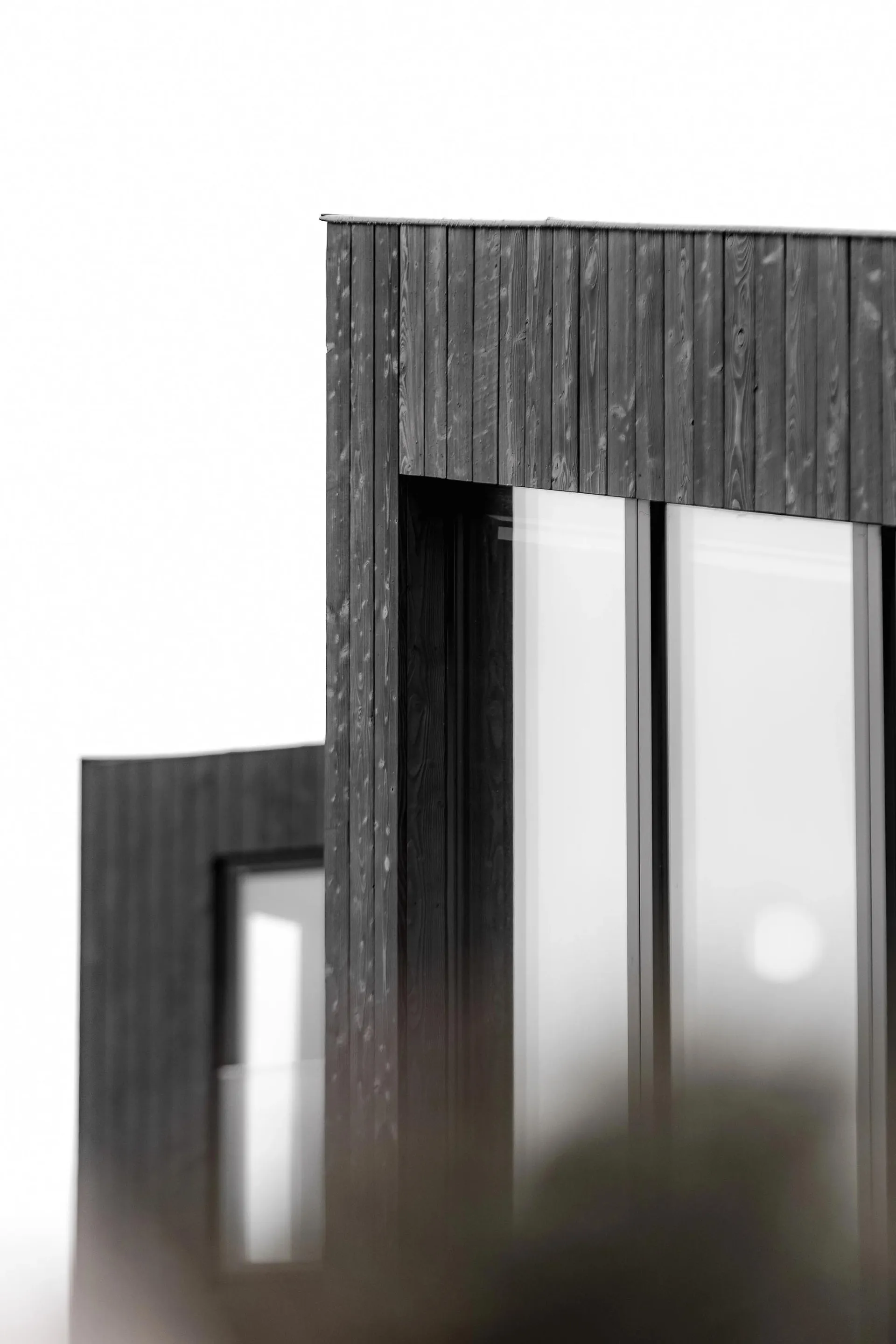 Modern building exterior featuring charred wooden panels and large glass windows.