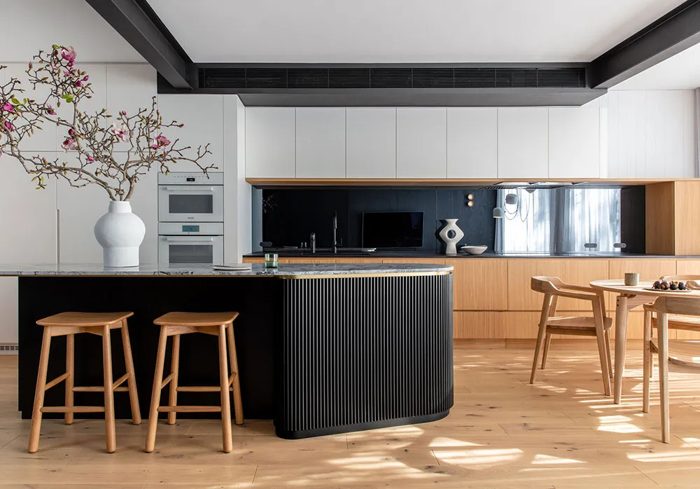 A modern minimalist kitchen with black and white color scheme, featuring a wooden island and marble countertops.