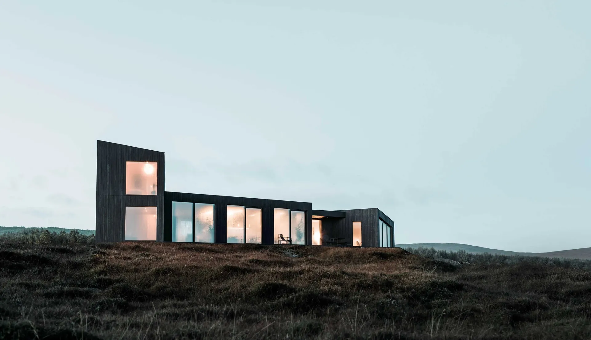 Modern house exterior featuring expansive windows, black structure, and minimalist design.