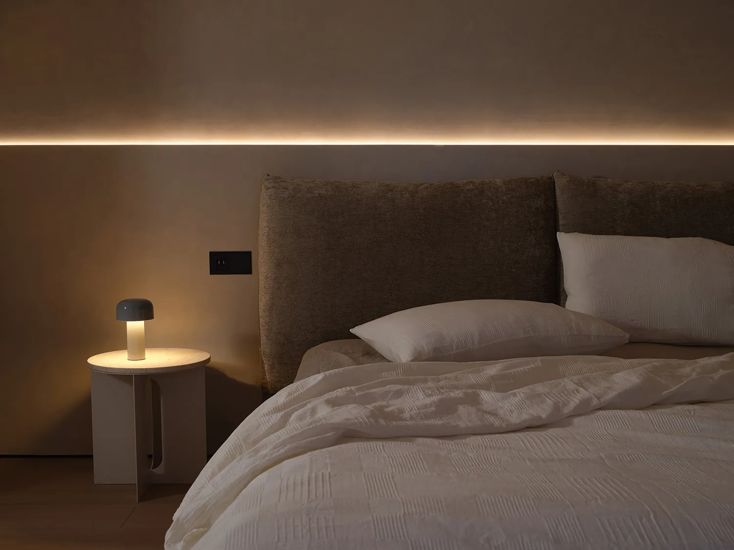 Minimalist bedroom with fabric headboard and linen bedding.