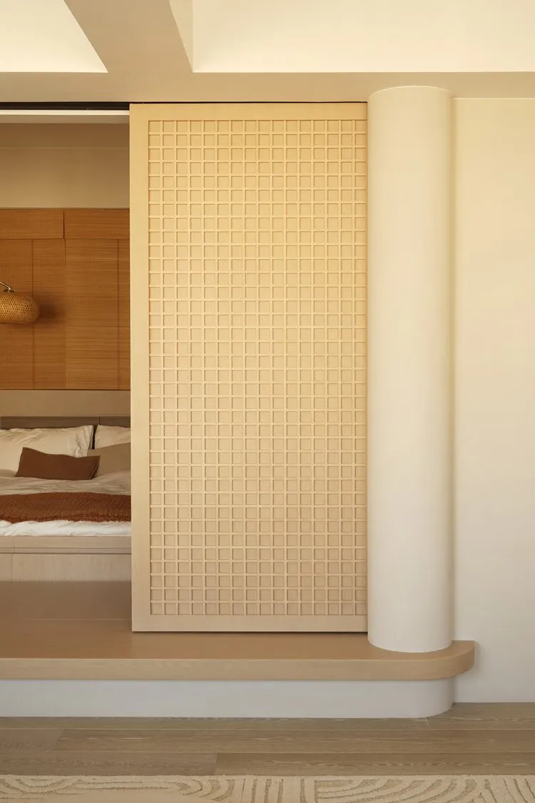Modern minimalist interior space with a light-colored tiled wall and wooden columns.