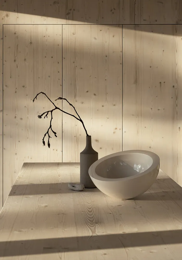 A minimalist interior with wooden furniture, featuring a bowl-shaped object and a vase with dried branches.