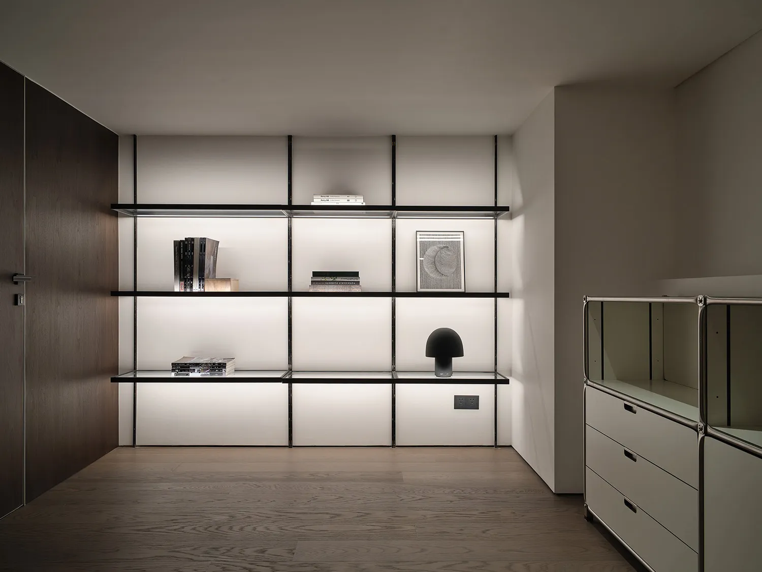Modern minimalist bookshelf with metal frame and glass shelves.