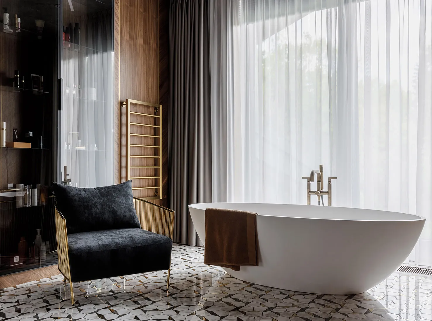 Modern bathroom with white marble floor, freestanding bathtub, and black armchair.