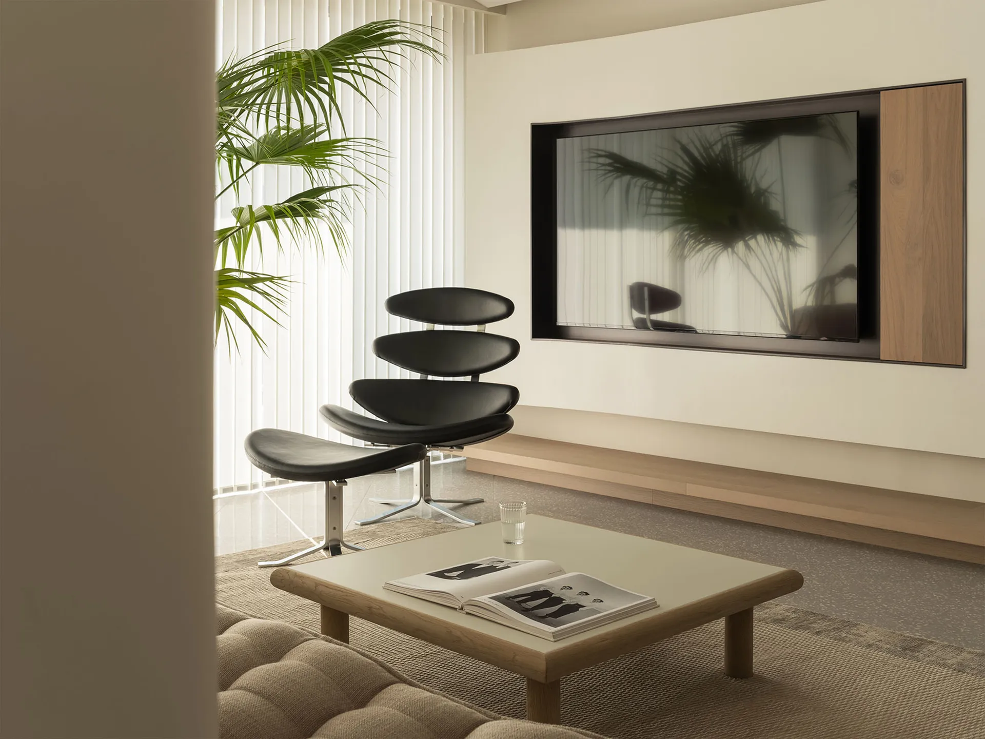 A modern living room with comfortable seating, a coffee table, a television, and a large window with a plant.