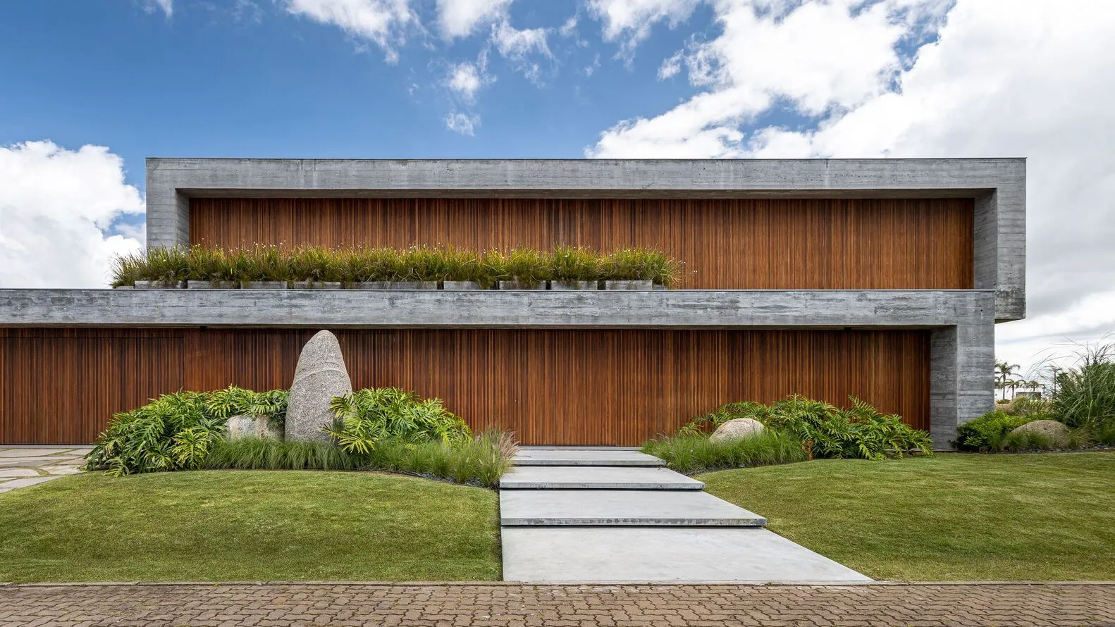 A modern residential building with a concrete exterior and greenery on the roof.