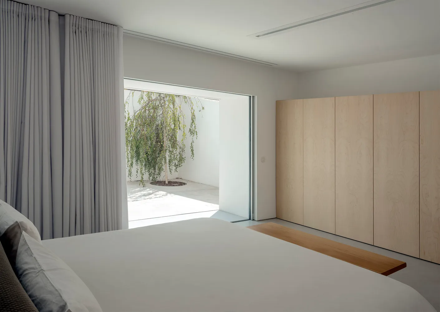 Minimalist bedroom featuring wood and concrete elements.