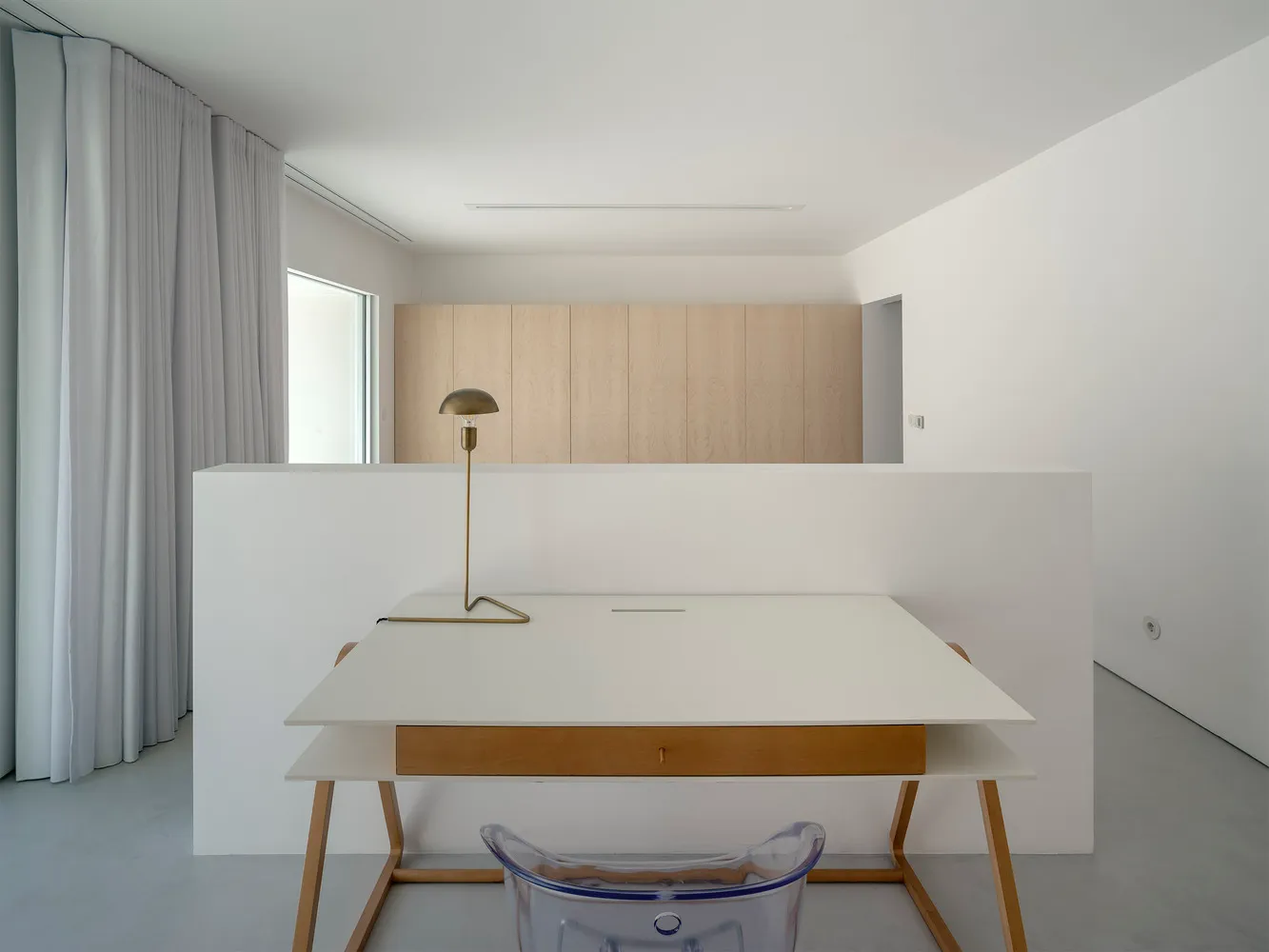 A minimalist office desk space with a white laminate top and a wooden legged chair in front of it.