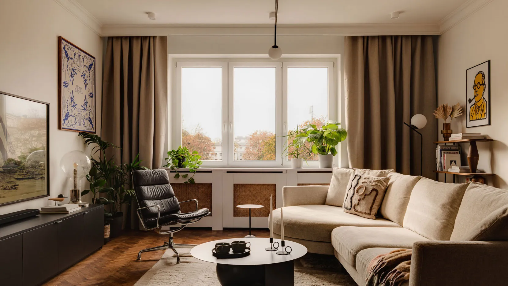 A modern living room with neutral-tones furniture, plants, and a large window.