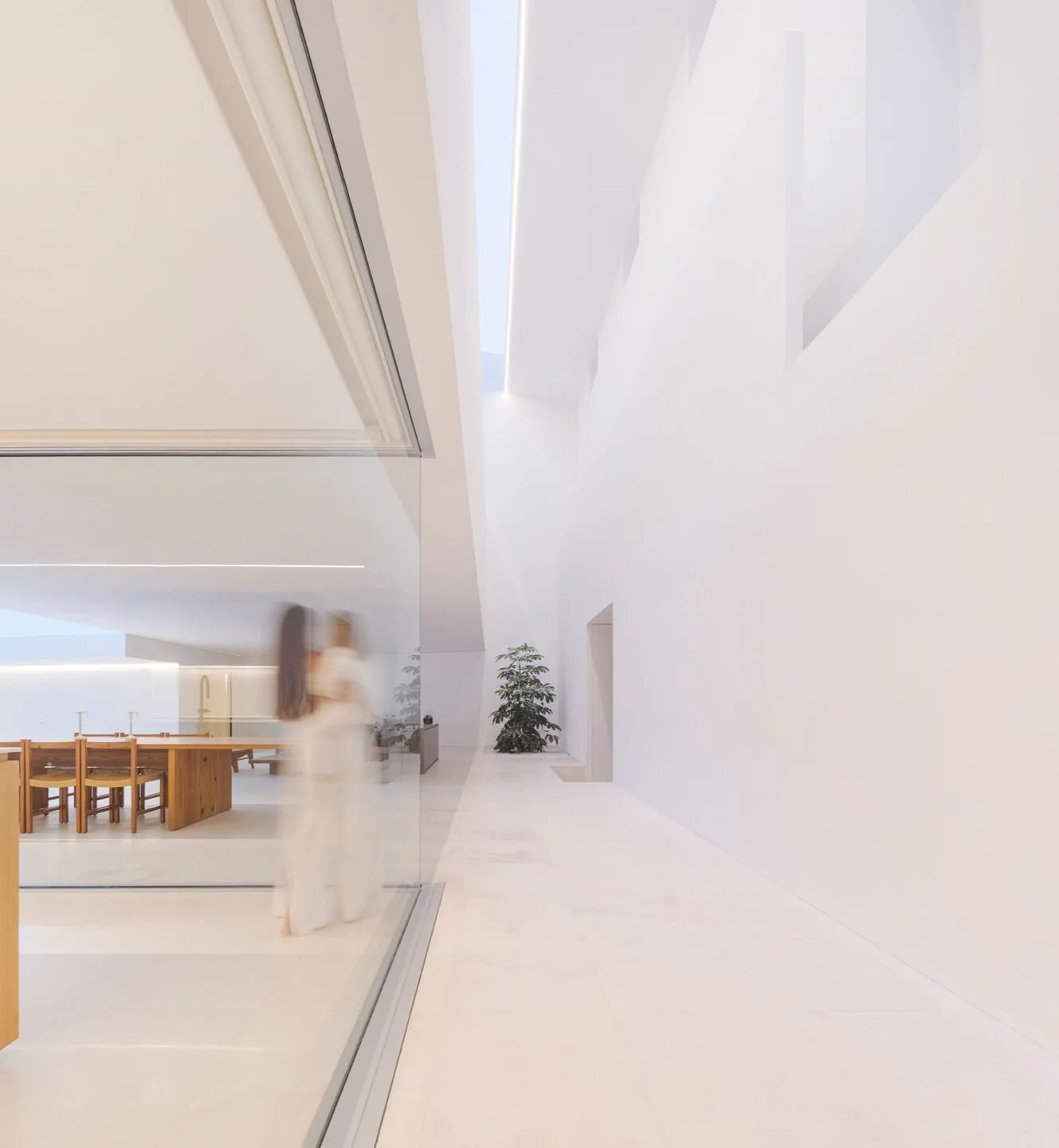 Modern minimalist interior with white marble floors and walls, featuring clean lines and natural light.