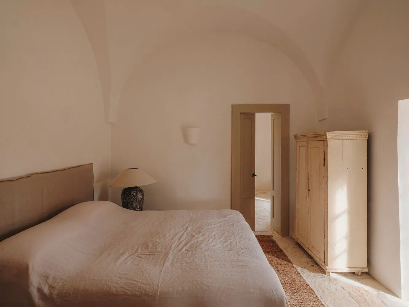 Minimalist bedroom with a bed, lamp, and white wardrobe
