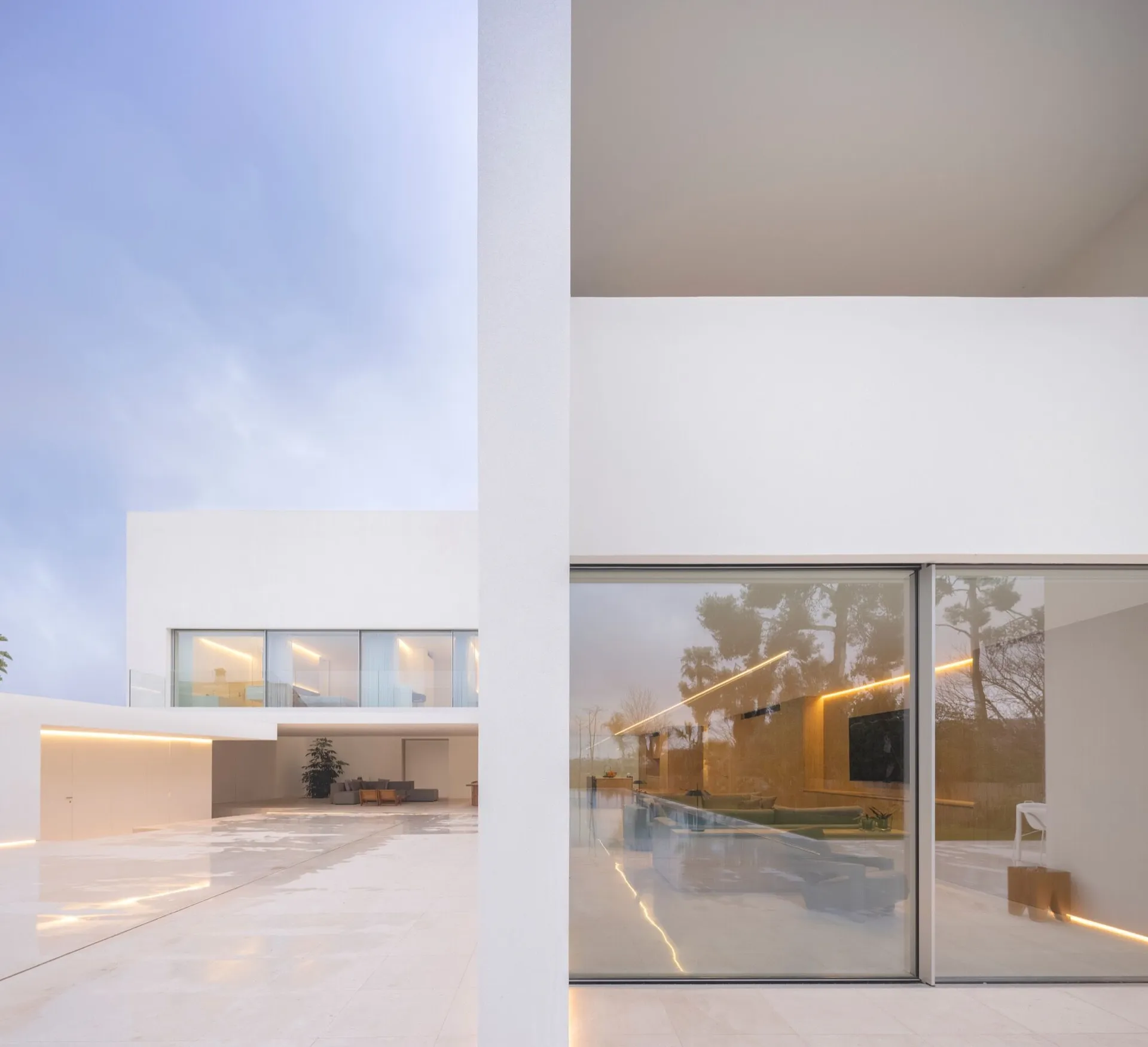 Modern minimalist white concrete dwelling with large glass windows and a sleek interior design.