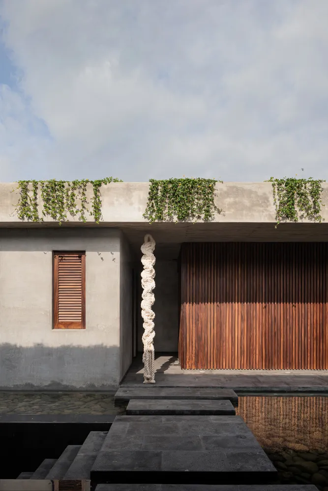 A modern exterior building facade with a plant wall on the rooftop and concrete steps.