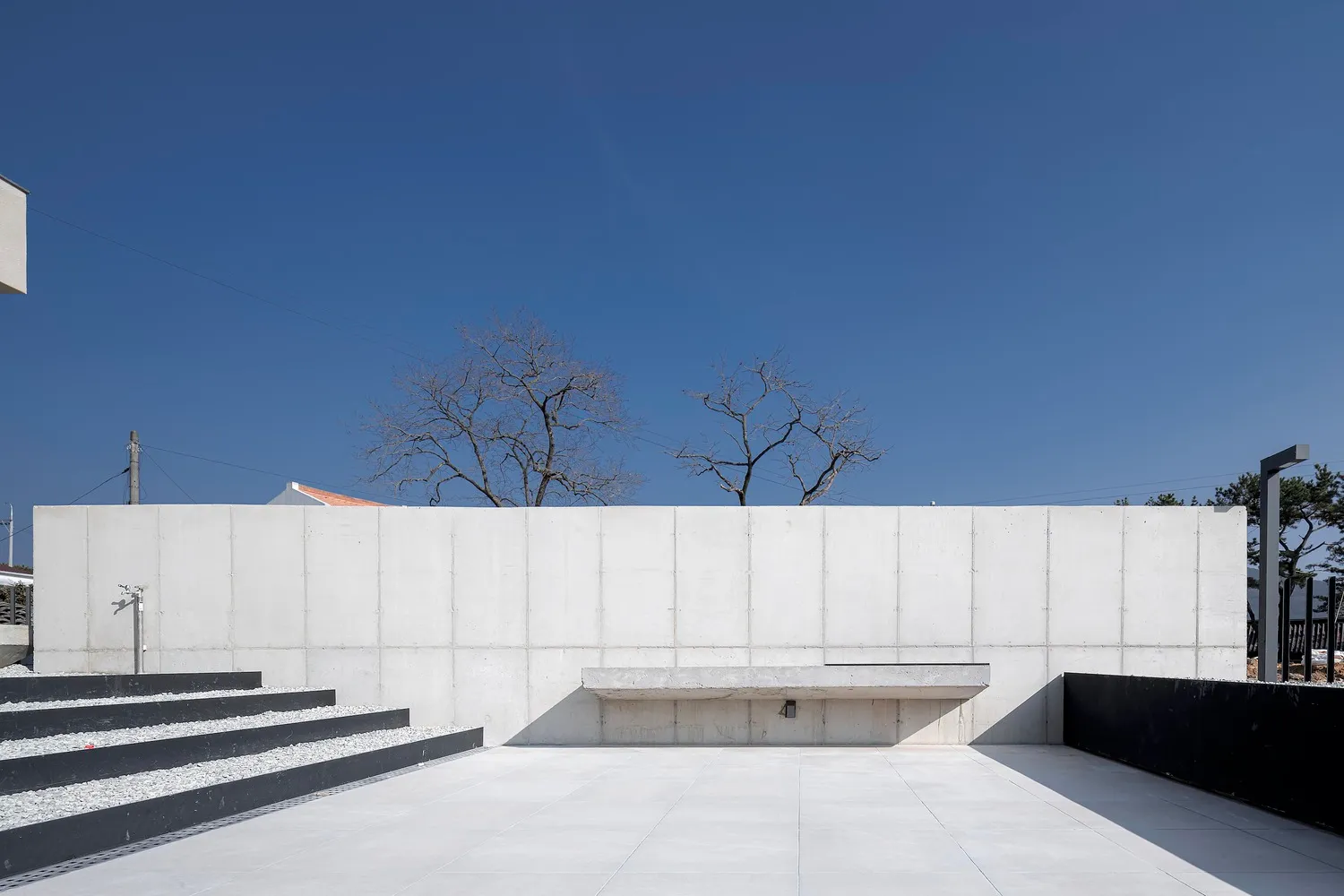 Modern minimalist architecture with concrete walls and steps, featuring a concrete bench and minimalist design elements.