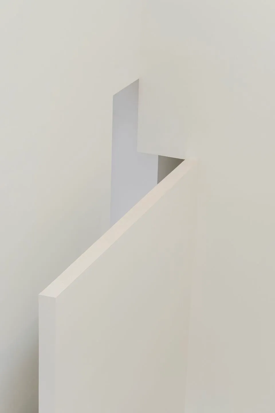 A minimalist hallway with white walls and a white staircase.