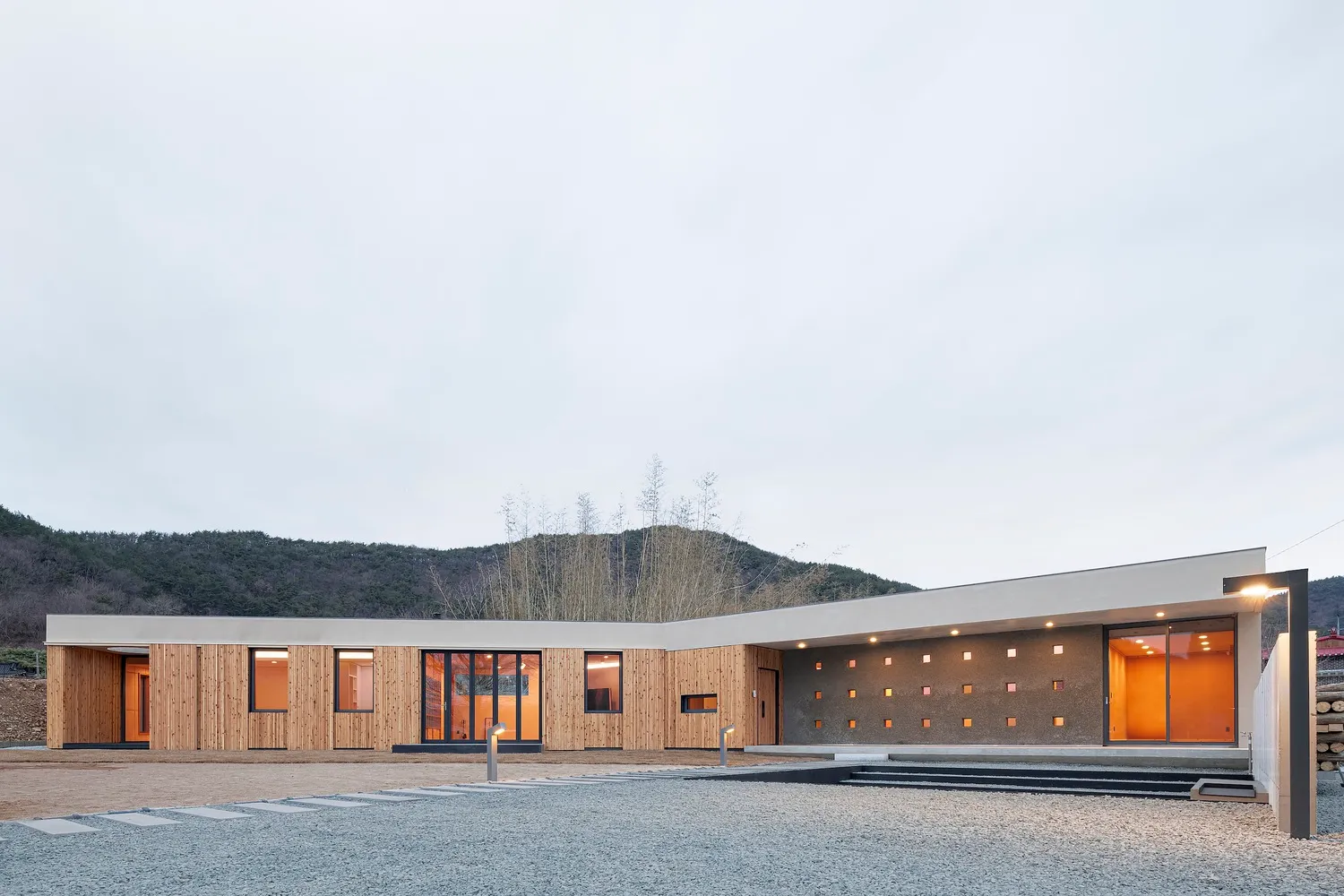 Modern house with wooden and concrete exterior and large glass windows.