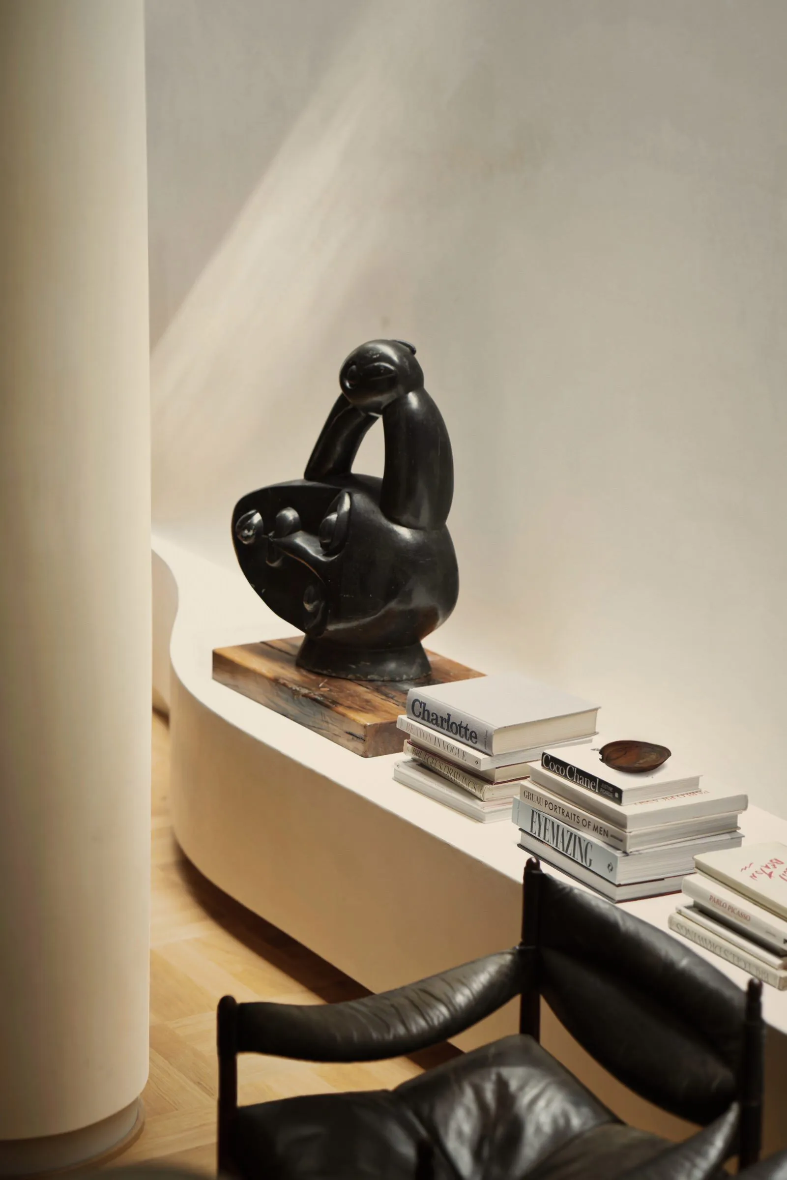 A modern interior decor featuring a bookshelf with a bird sculpture and books placed on a white shelf.