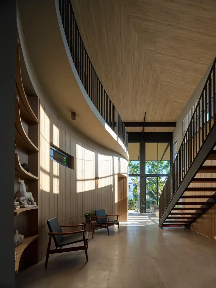 A modern interior with wooden walls and floors, featuring an open space and stairs.