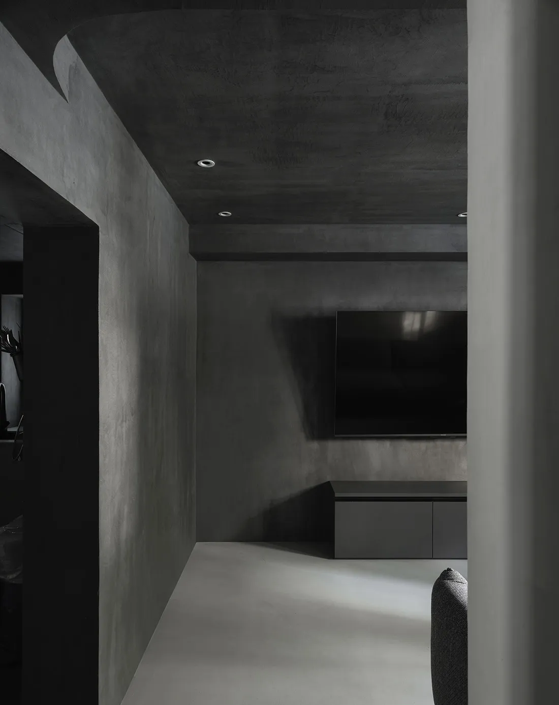 A modern living room featuring minimalist concrete walls and furniture.