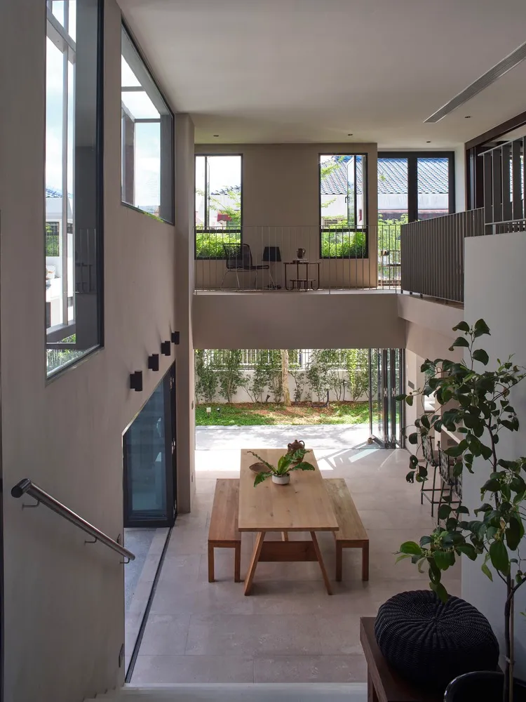 A modern living room with wooden table, concrete walls, and glass windows.