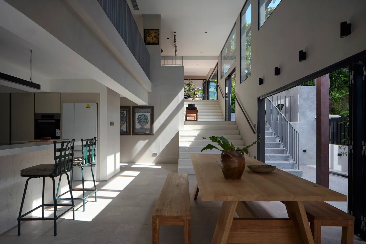 Modern minimalist residential interior featuring wood dining table and concrete floor.