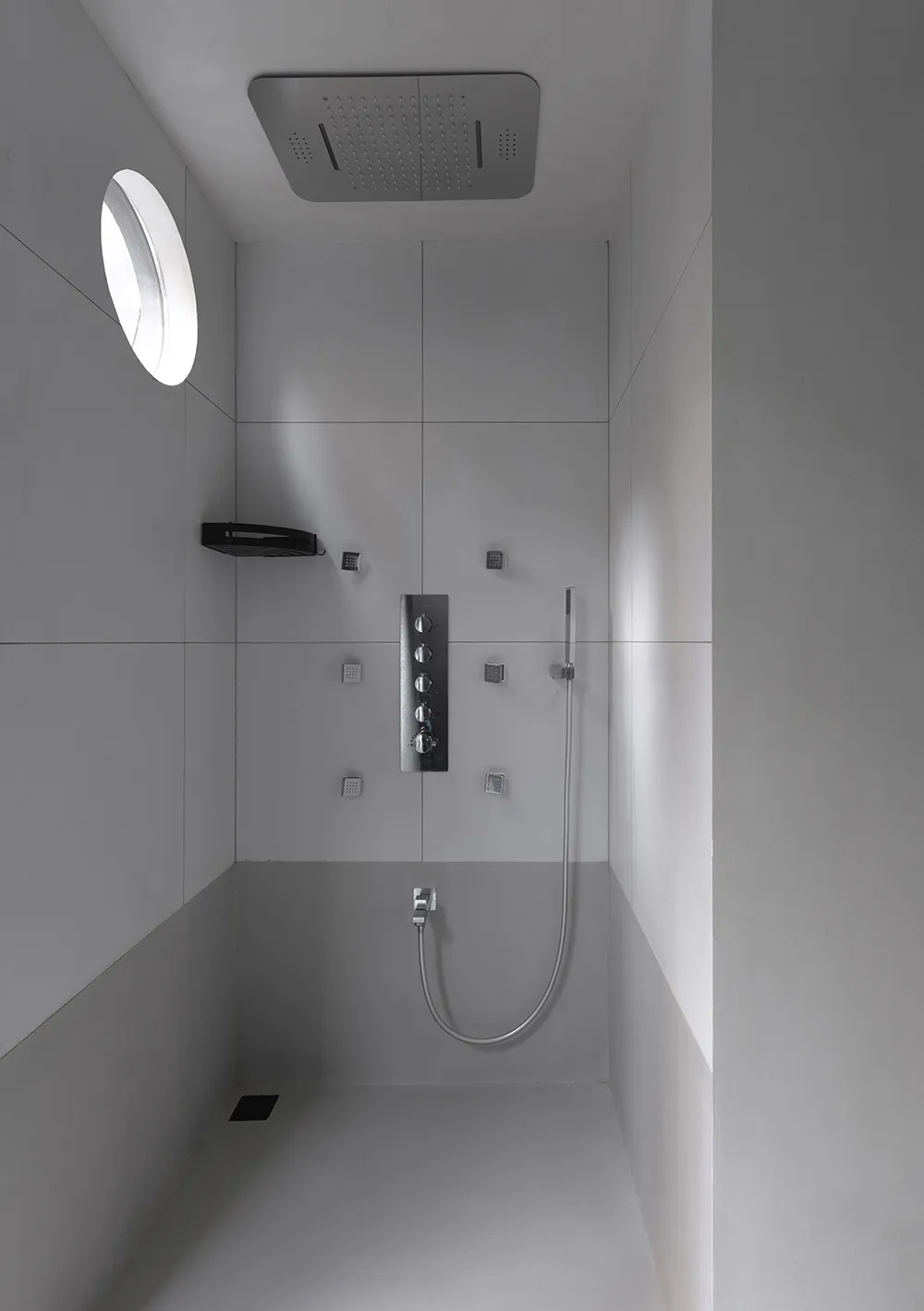 A minimalist white bathroom with modern fixtures and a circular window.