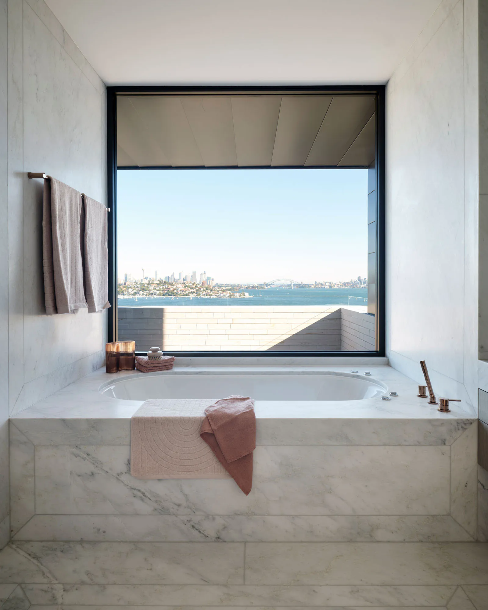 Modern minimalist bathroom with marble finish and large window overlooking the ocean.