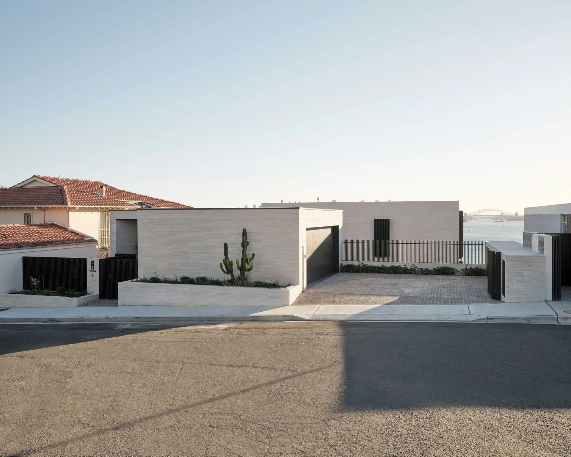 Concrete exterior with black railings and cacti planters in front of a house.