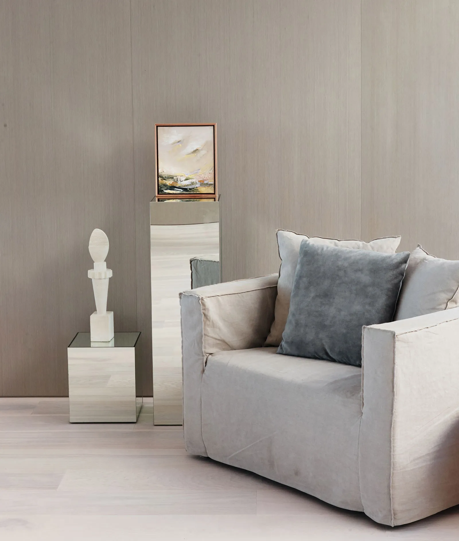 A modern living room with neutral-toned decor, featuring a comfortable armchair, a small side table with a glass tabletop, an