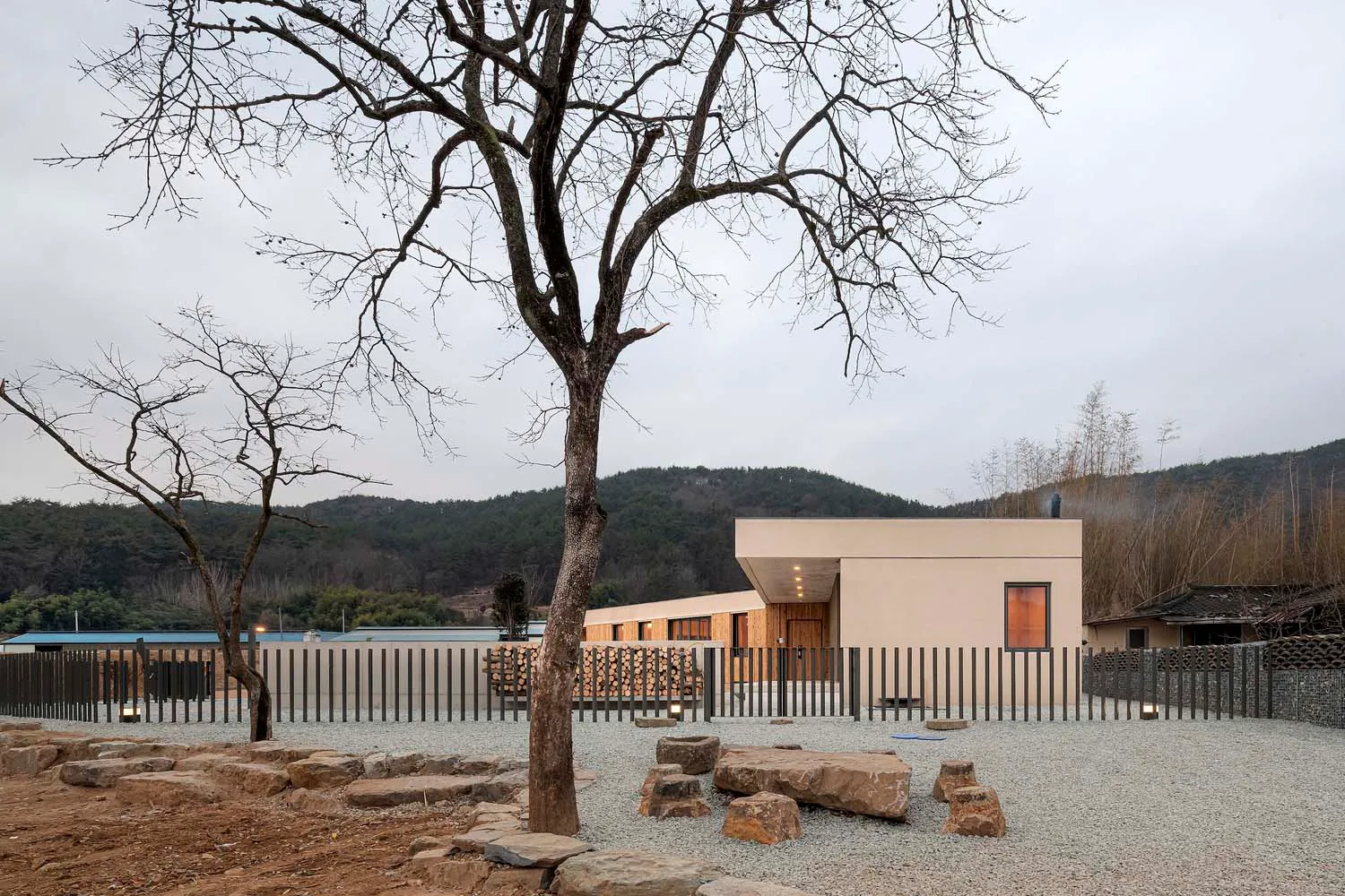 A modern residential home with a minimalist exterior featuring wood, stone, and metal.