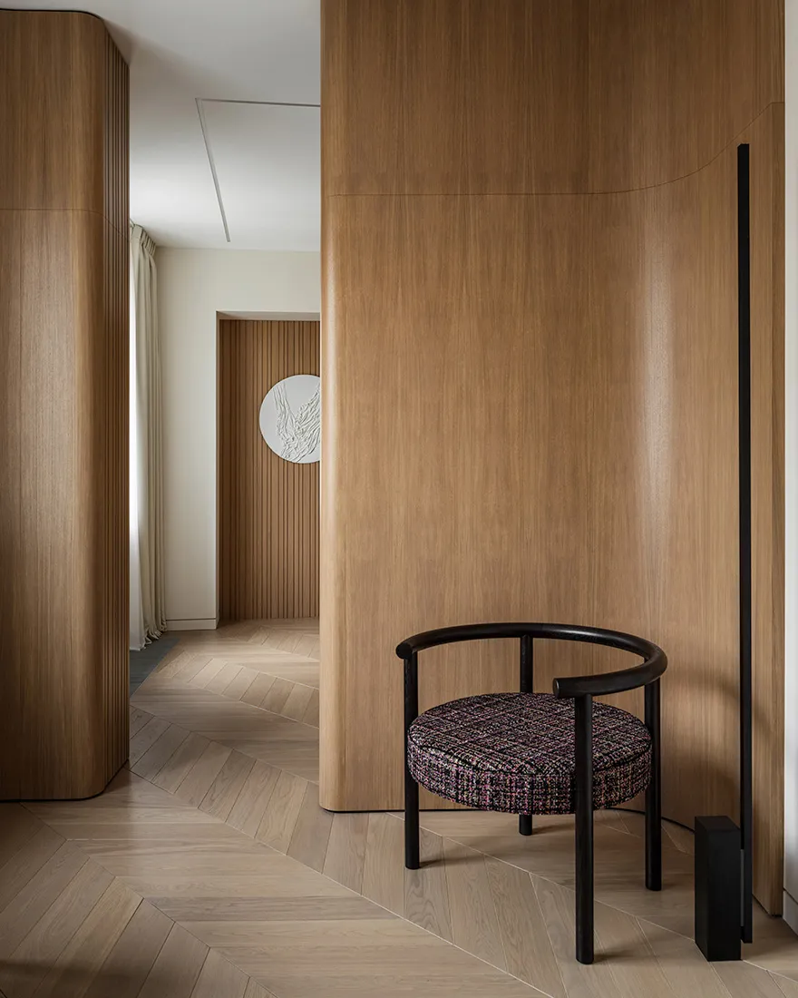 A modern interior design featuring a wooden wall and a circular chair with a colorful cushion.