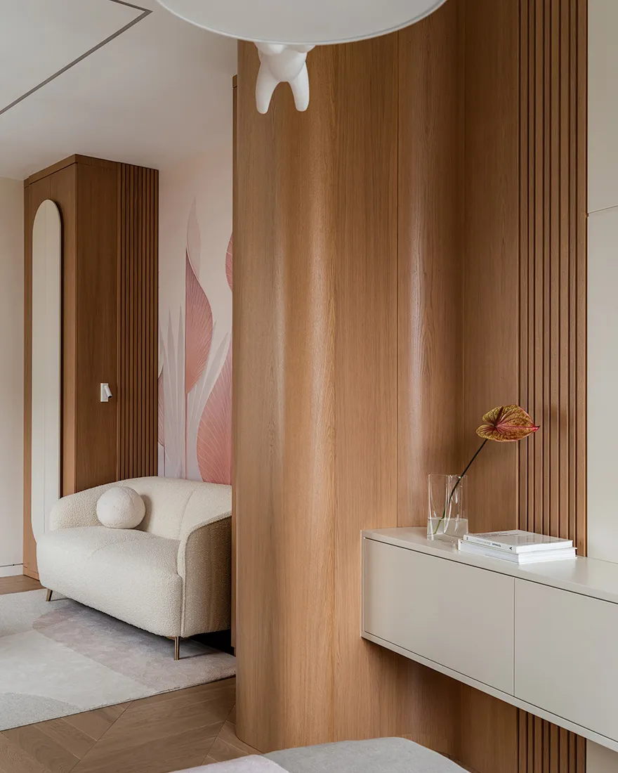 A modern living room with wooden paneling, a white sofa, and pink floral wallpaper.