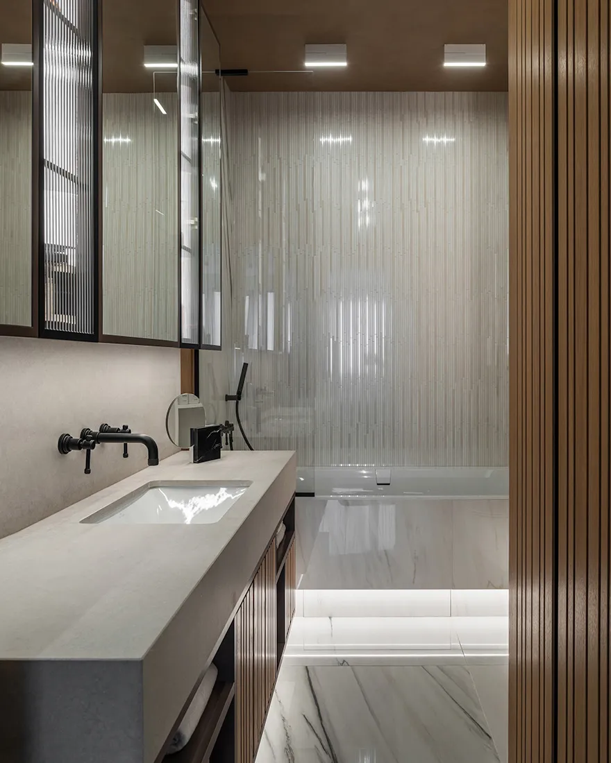 Modern bathroom with marble finishes, featuring a minimalist design with sleek, white fixtures and a large, textured glass sh