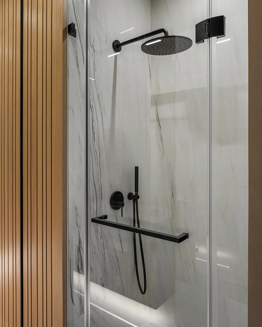 Modern bathroom shower with marble tiles and black steel fixtures