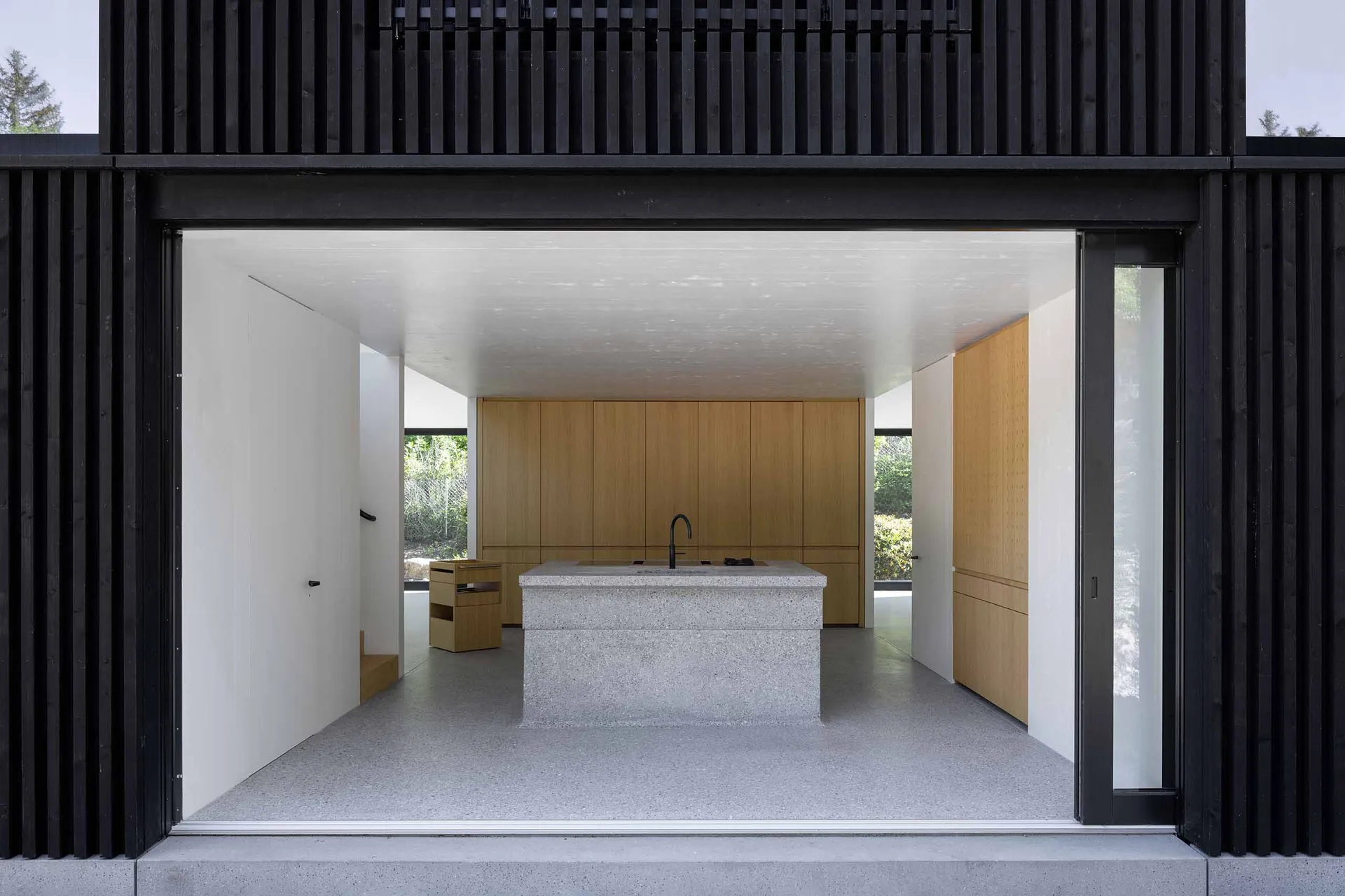 A modern kitchen with a concrete island and wooden cabinets.