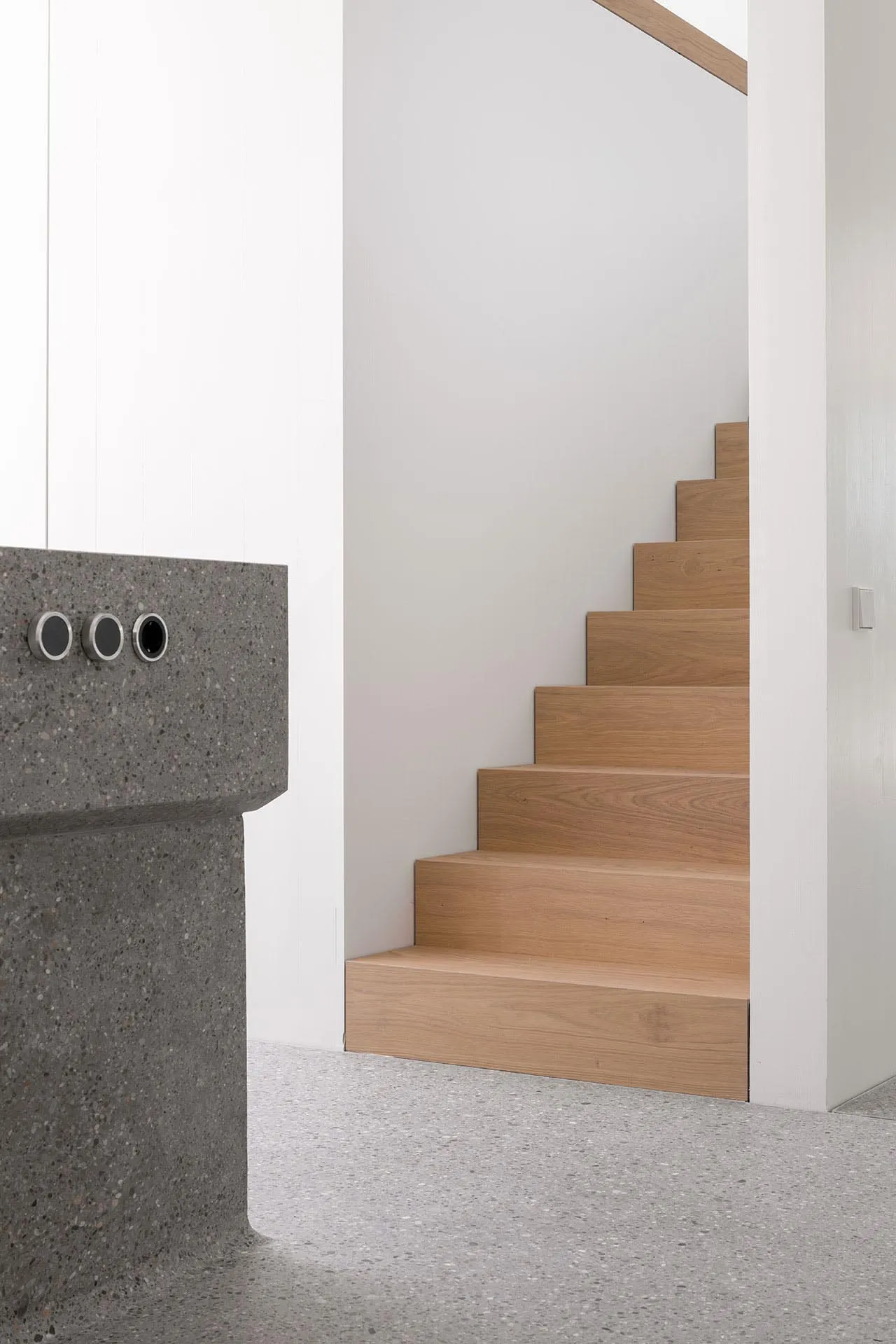 A minimalist modern staircase with wooden steps and a concrete foot step.