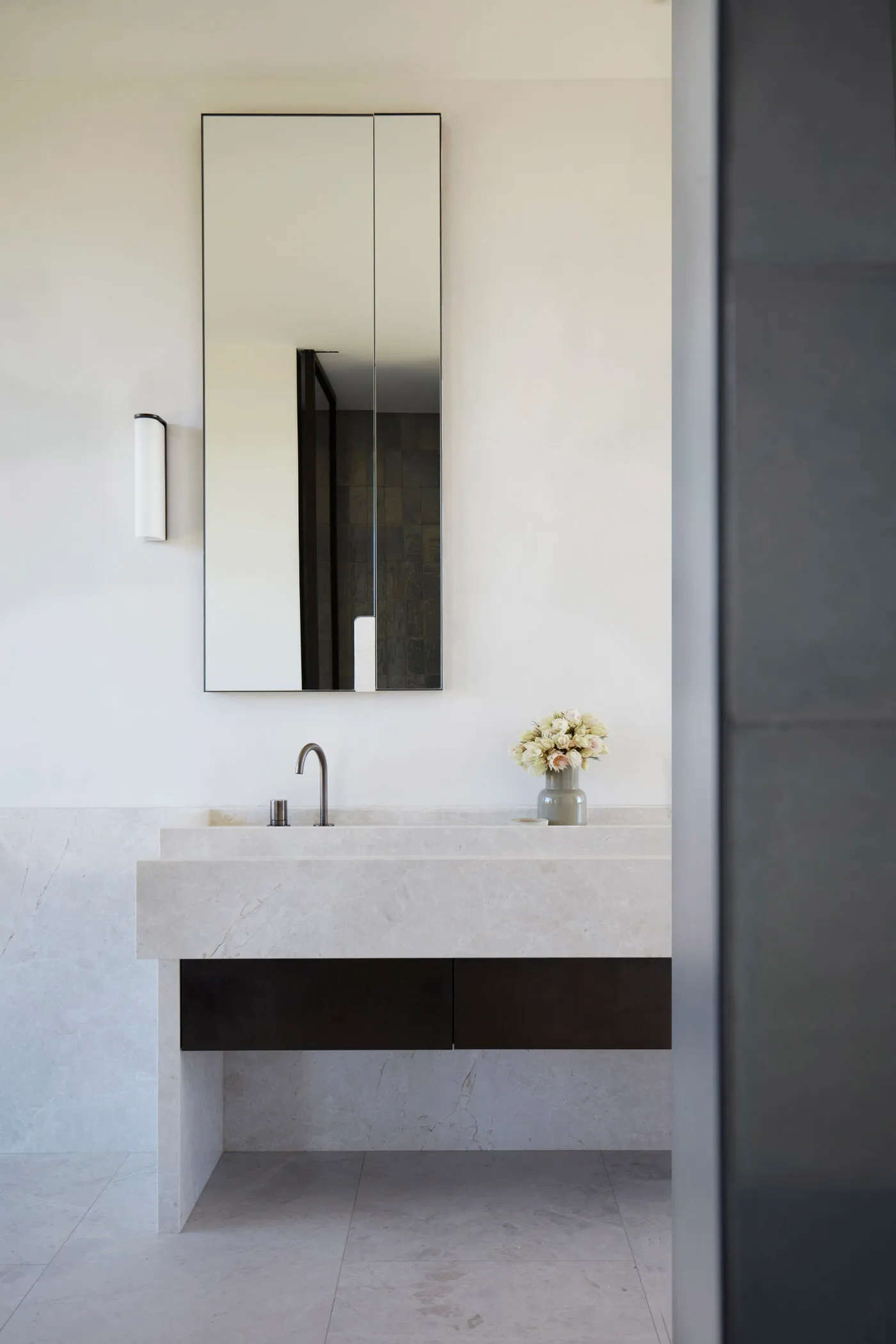 Modern minimalist bathroom featuring a marble countertop and a tall rectangular mirror.
