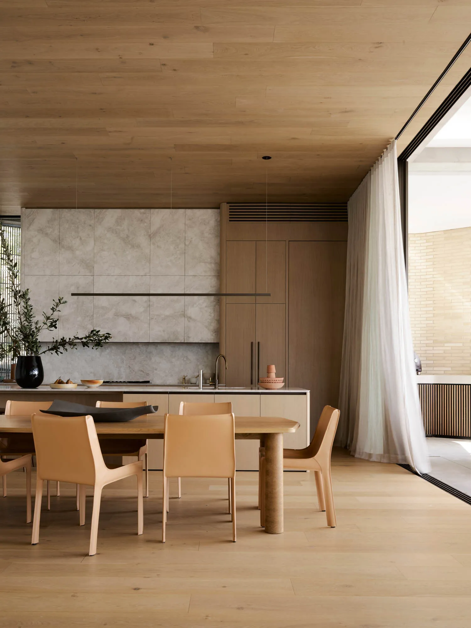 A photograph of a modern residential dining space featuring wood and marble elements.