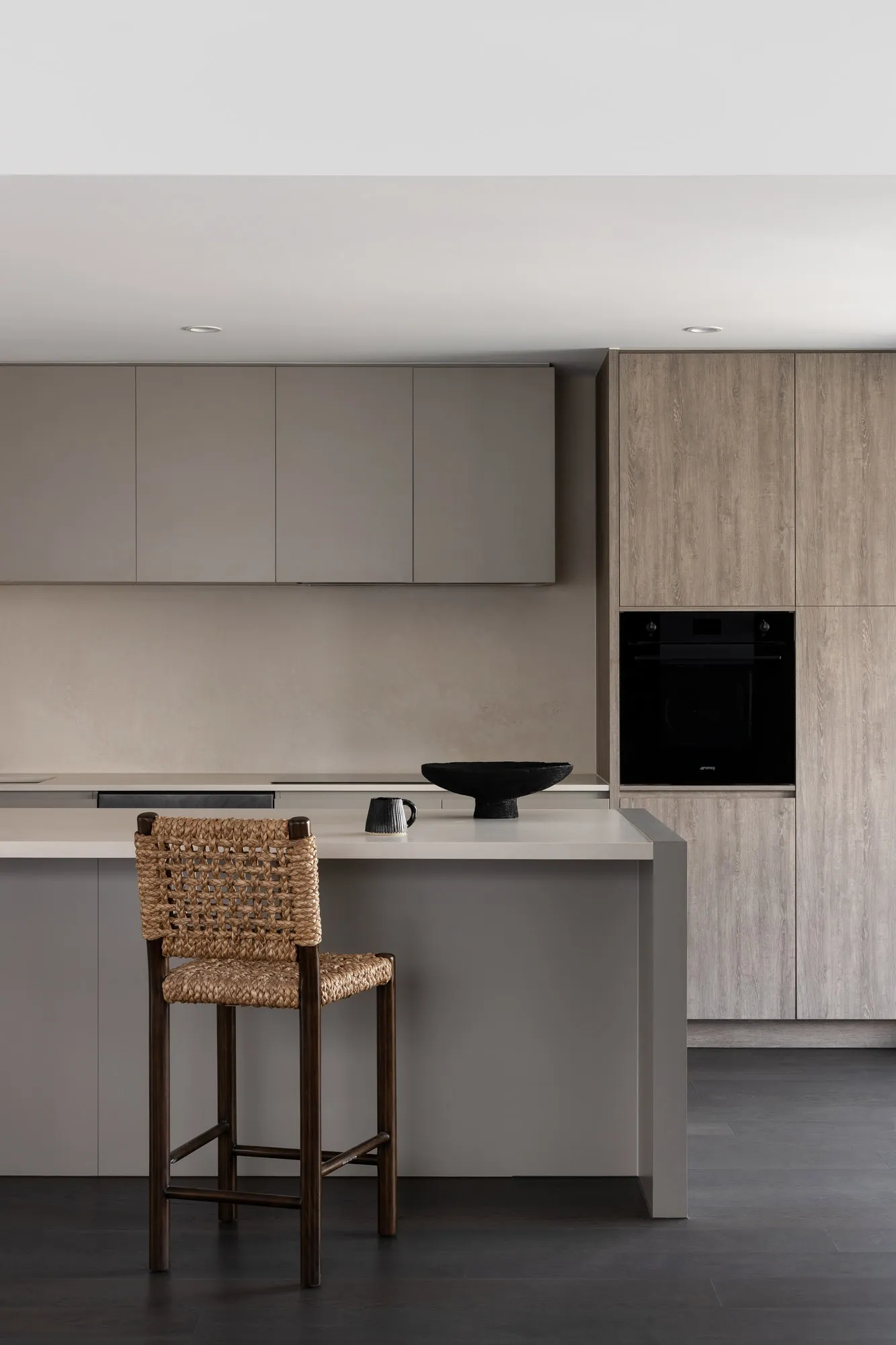Modern minimalist kitchen with wooden cabinets, a white countertop, and a black decorative bowl.