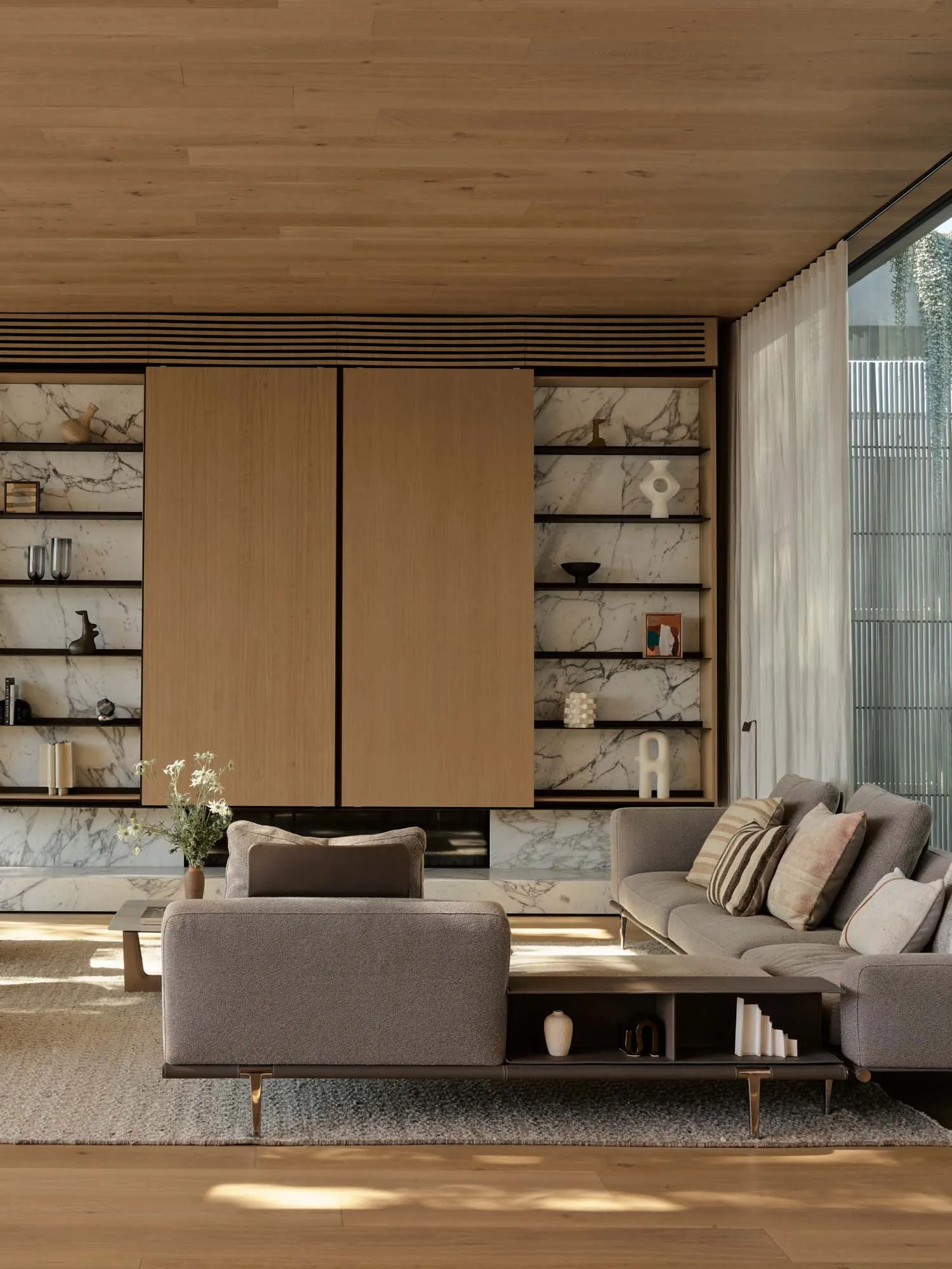 Modern living room with wood paneling, marble wall, and fabric sofas and ottoman.