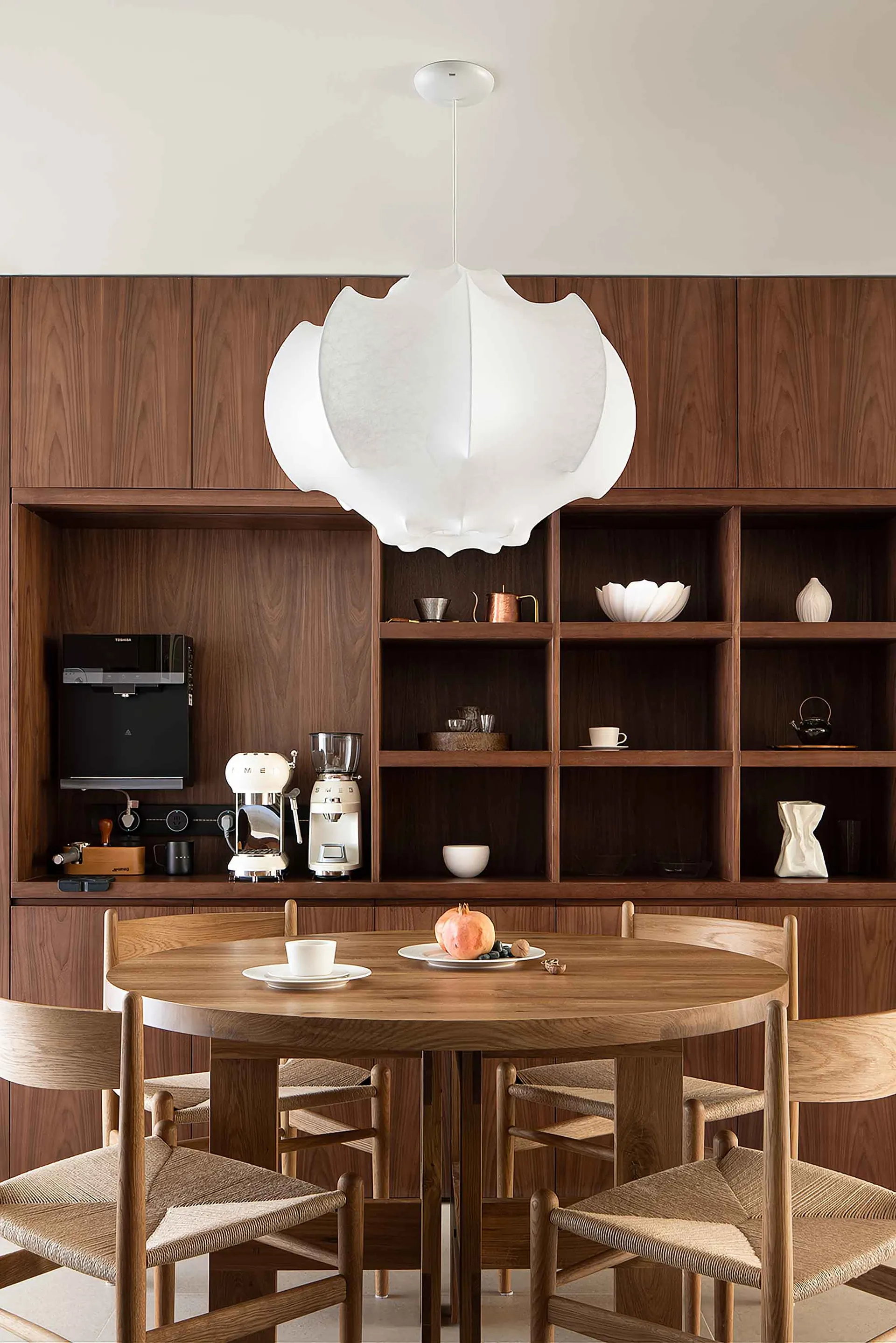A modern residential space featuring wooden furniture and a large pendant light.