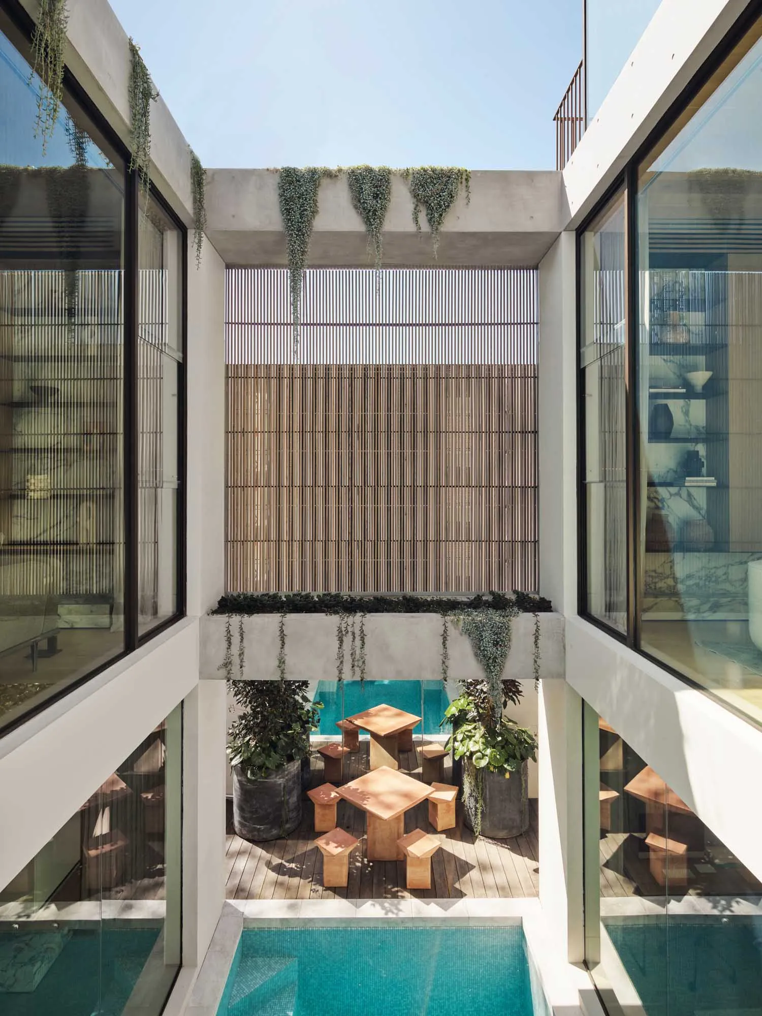 Modern interior design featuring concrete and glass materials on a terrace with outdoor seating and a swimming pool.