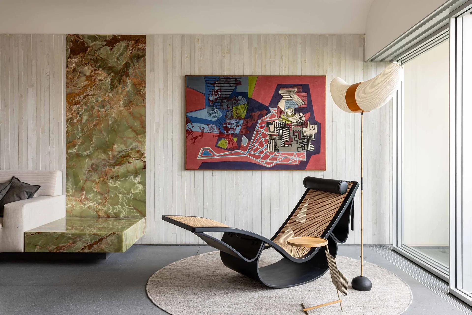 A modern living room featuring a statement marble floor lamp and abstract artwork on the wall