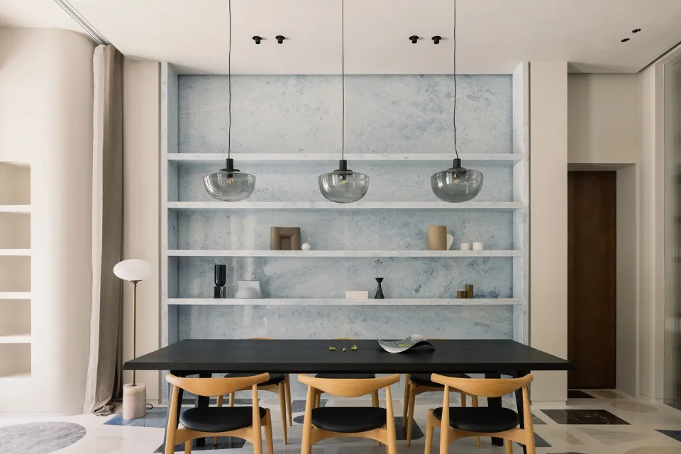 Modern dining room featuring a wooden table, chairs, and a marble backdrop.