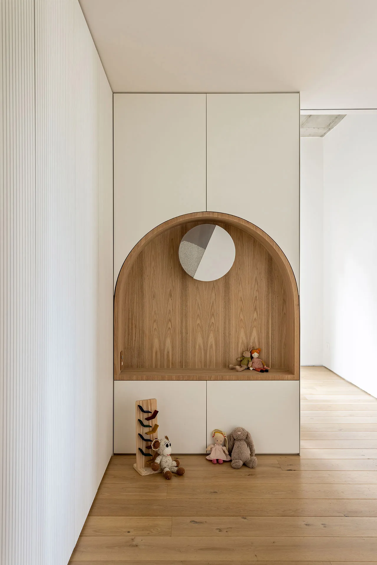 A modern interior design featuring a minimalist space with wood and white paneling, displaying several plush toys underneath