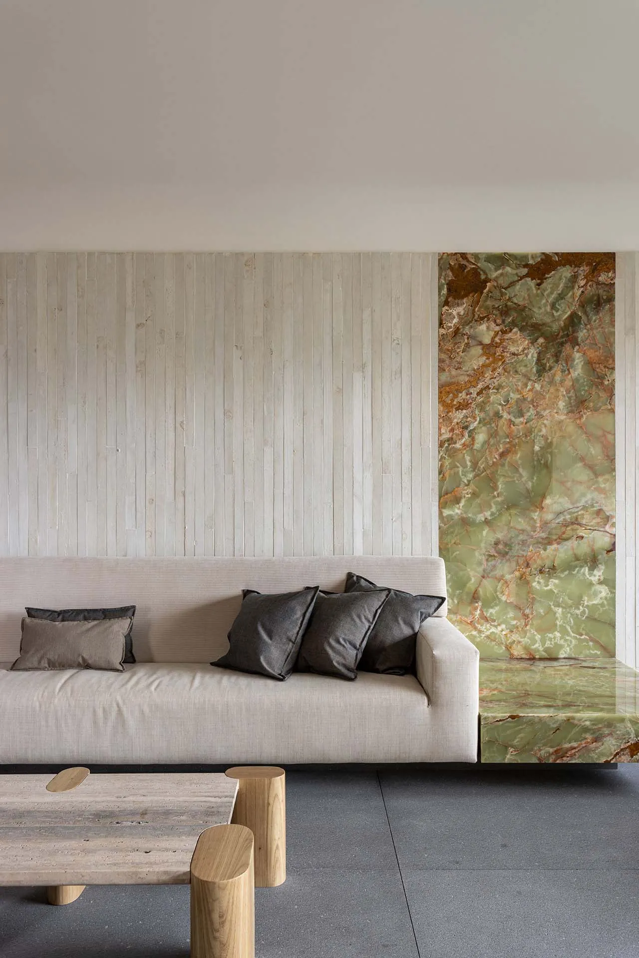 Modern living room featuring minimalist furniture, marble accents, and concrete floor.