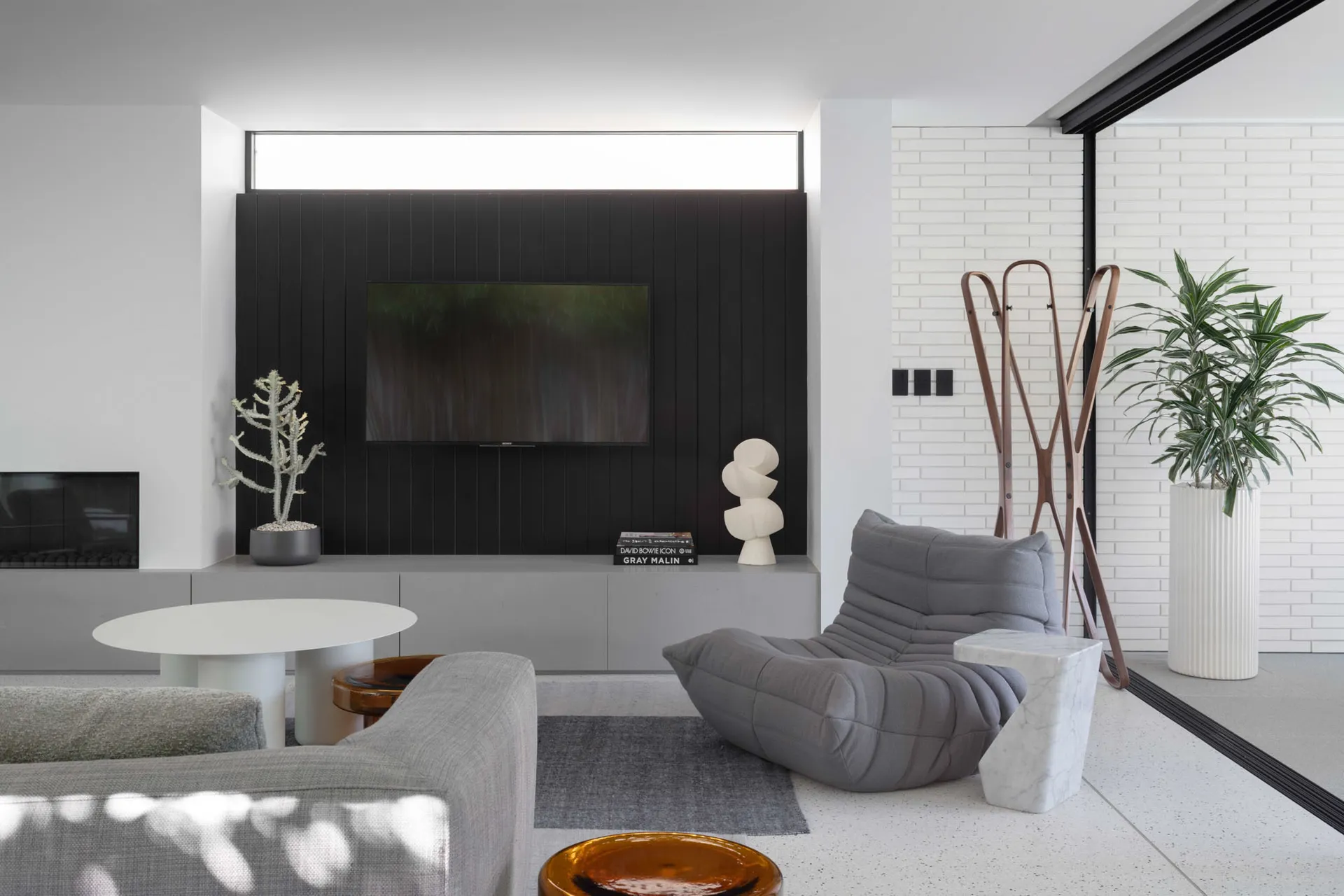 Modern minimalist living room with concrete and marble finishes, featuring a couch, chair, and potted plant.